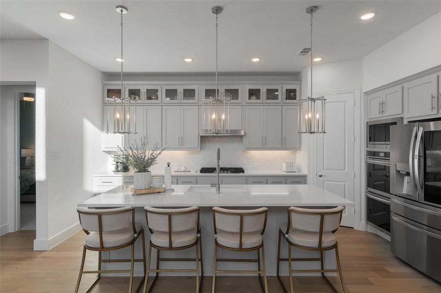 Kitchen with light wood finished floors, visible vents, stainless steel appliances, and light countertops