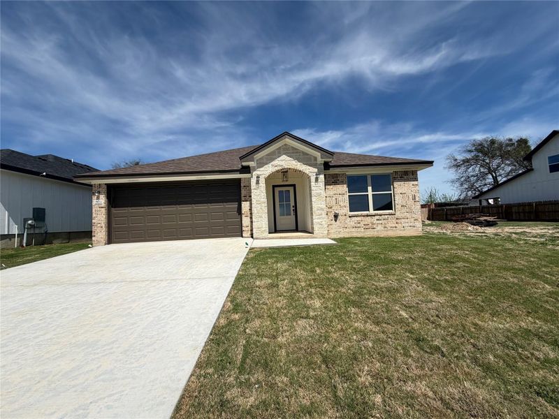 A newly constructed residence features a charming brick and stone facade with an attached garage. A newly constructed residence features a charming brick and stone facade with an attached garage.