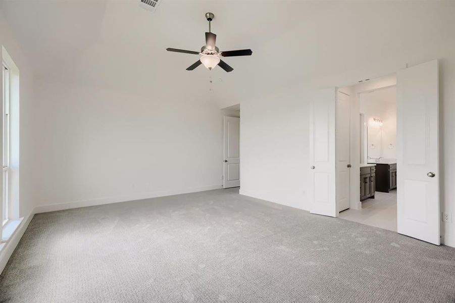 Spacious room featuring light gray carpeting, neutral wall finishes, and a ceiling fan with integrated lighting