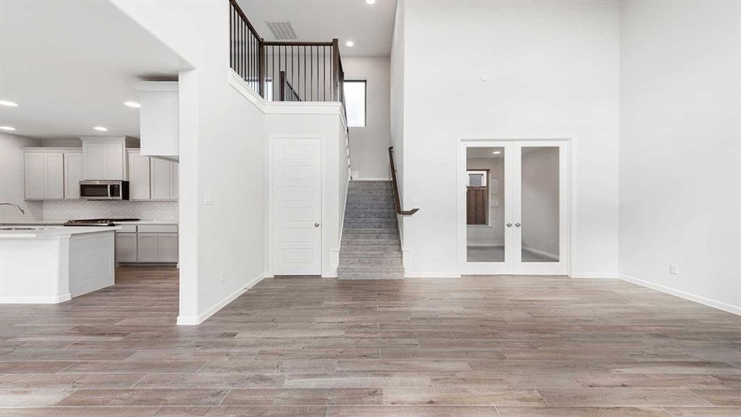 Unfurnished living room with a towering ceiling, sink, and light hardwood / wood-style flooring