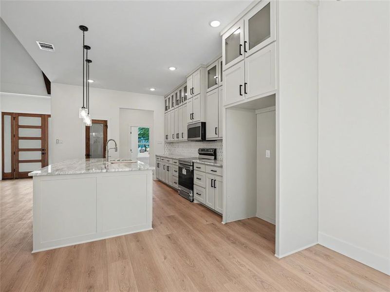 Modern kitchen featuring a central island with a sink and a light-toned countertop Modern kitchen featuring a central island with a sink and a light-toned countertop