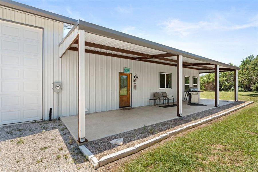 Back porch with gutters, firepit area, landscaping, and access to shop as well.