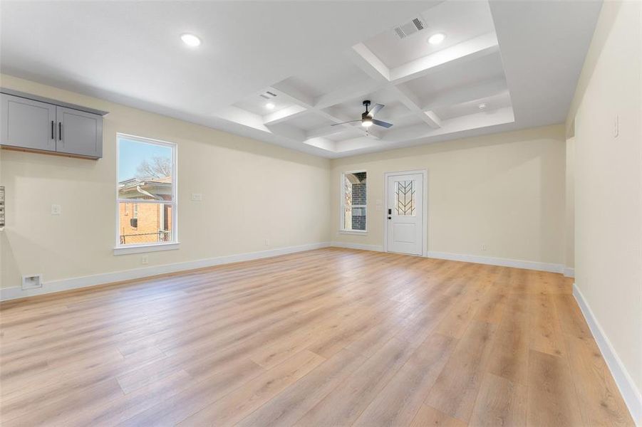 Spare room with ceiling fan, coffered ceiling, beam ceiling, and light hardwood / wood-style flooring