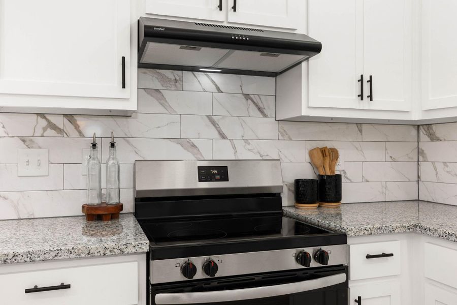 This kitchen features a modern aesthetic, highlighted by a stainless steel electric stove paired with a sleek range hood. This kitchen features a modern aesthetic, highlighted by a stainless steel electric stove paired with a sleek range hood.
