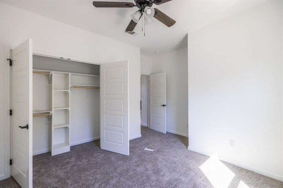 Unfurnished bedroom featuring dark colored carpet, a closet, and ceiling fan