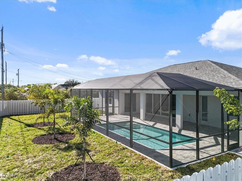 Rear view of property with a fenced backyard, a sunroom, glass enclosure, and roof with shingles