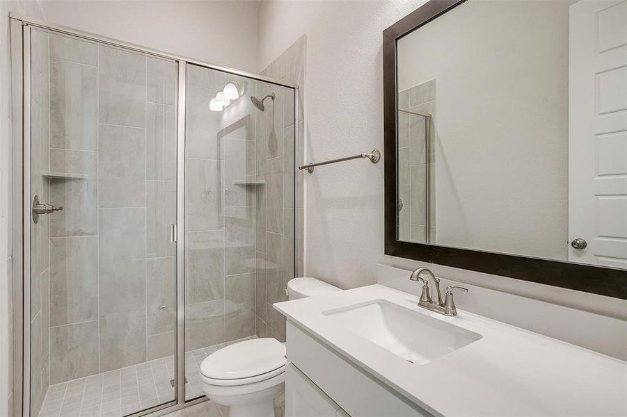 Bathroom with vanity, toilet, and a shower with door