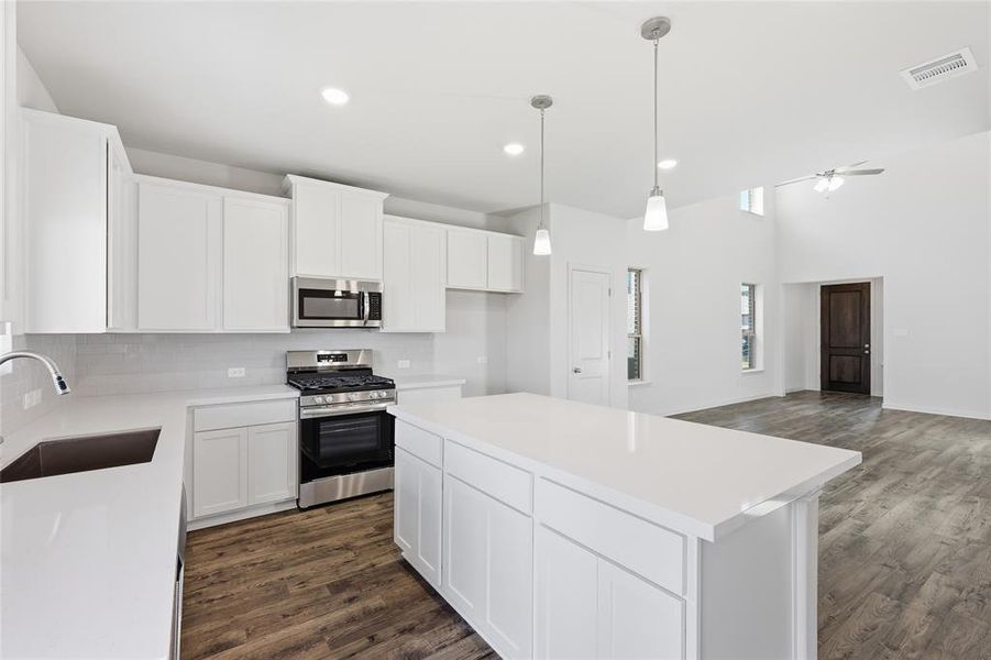 Contemporary kitchen featuring white cabinetry, stainless steel appliances, a center island with countertop seating, and wood-finish flooring