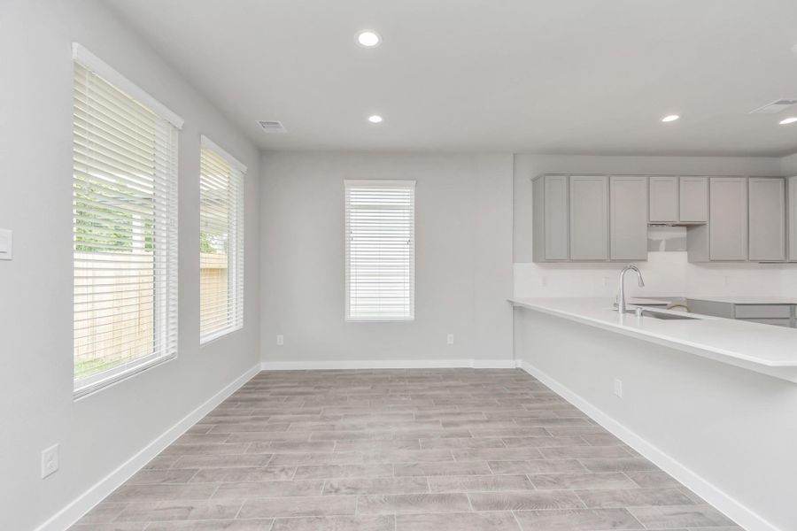 An inviting dining space seamlessly woven into the open concept, connecting the family room and kitchen. Revel in the stunning floors, soothing paint palette, and the crowning touch of a sleek chandelier – a perfect setting for shared meals and cherished moments. Sample photo of completed home with similar floor plan. Actual colors and selections may vary. An inviting dining space seamlessly woven into the open concept, connecting the family room and kitchen. Revel in the stunning floors, soothing paint palette, and the crowning touch of a sleek chandelier – a perfect setting for shared meals and cherished moments. Sample photo of completed home with similar floor plan. Actual colors and selections may vary.