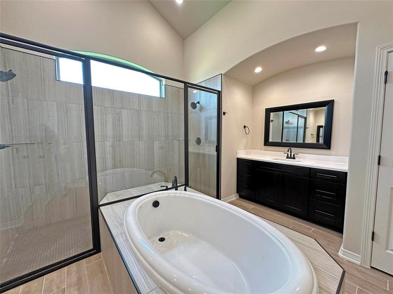 Bathroom with a garden tub, walk in shower, vanity, wood tiled floors, and recessed lighting