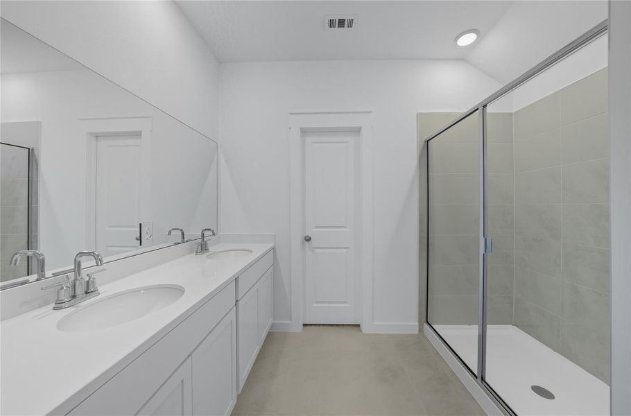 Bathroom featuring a shower stall, double vanity, and light tile patterned floors Bathroom featuring a shower stall, double vanity, and light tile patterned floors