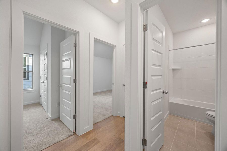 A well-lit hallway with various rooms including a bathroom and additional living spaces.