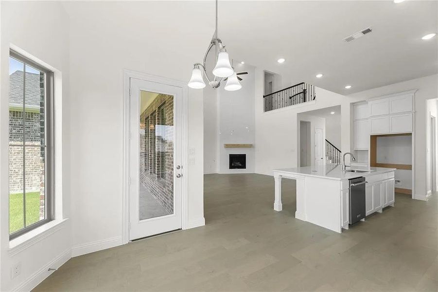 Kitchen featuring white cabinets, a center island with sink, hanging light fixtures, and an inviting chandelier