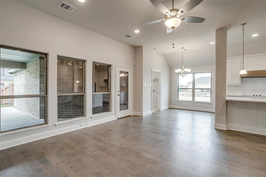 Unfurnished living room featuring vaulted ceiling, ceiling fan with notable chandelier, and wood-type flooring