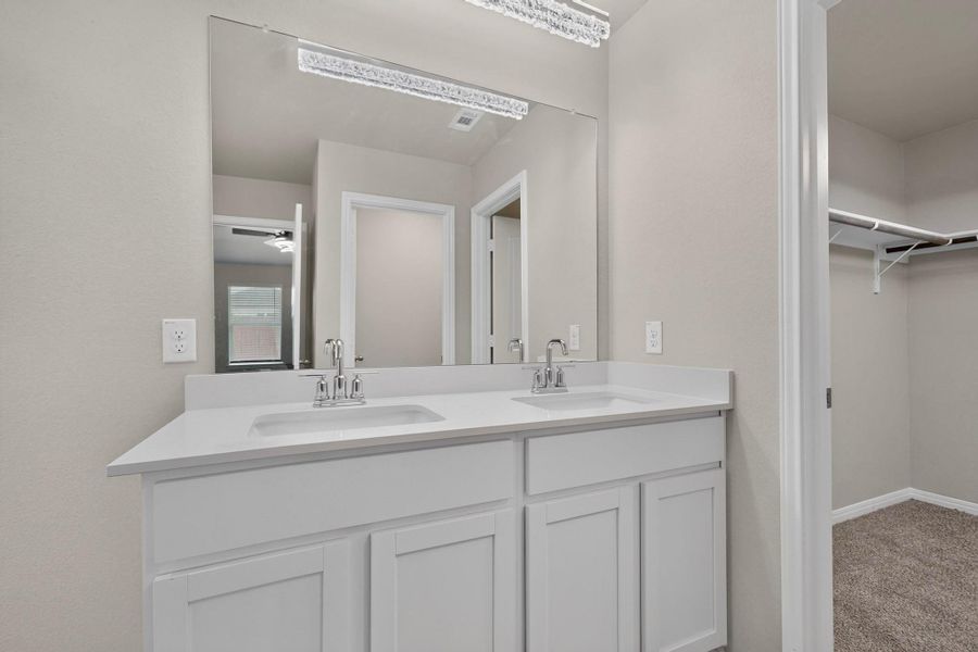 Clean lines and a double vanity define this modern bathroom space with adjacent closet.