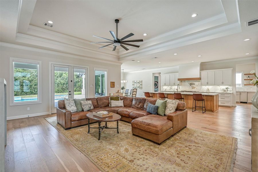 Designed with an effortless indoor-outdoor connection, the spacious family room opens to the island kitchen while a wall of windows & glass doors overlooks the backyard pool. Wood flooring, a dramatic tray ceiling & extensive recessed lighting continue throughout.