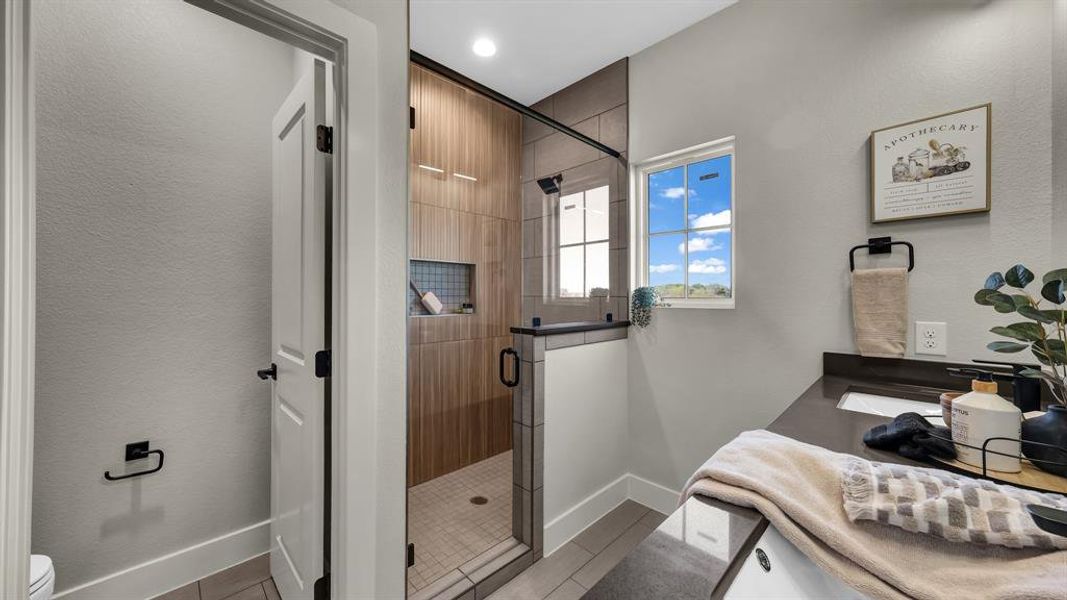 Bathroom with a shower stall, double vanity, and a textured wall