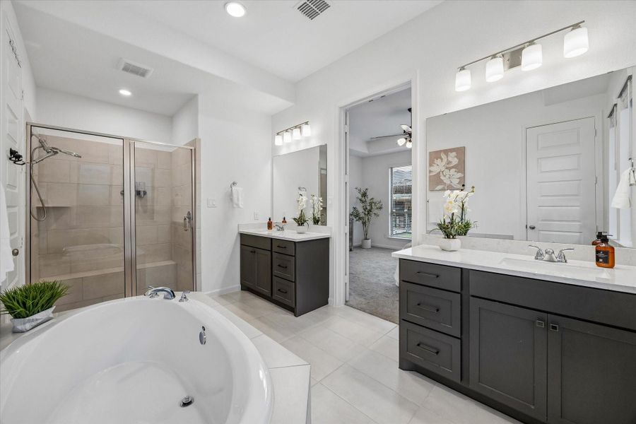 Separate vanities provide plenty of elbow room, storage, and polished style, while bright lighting and clean finishes create a fresh, relaxing start and end to each day.