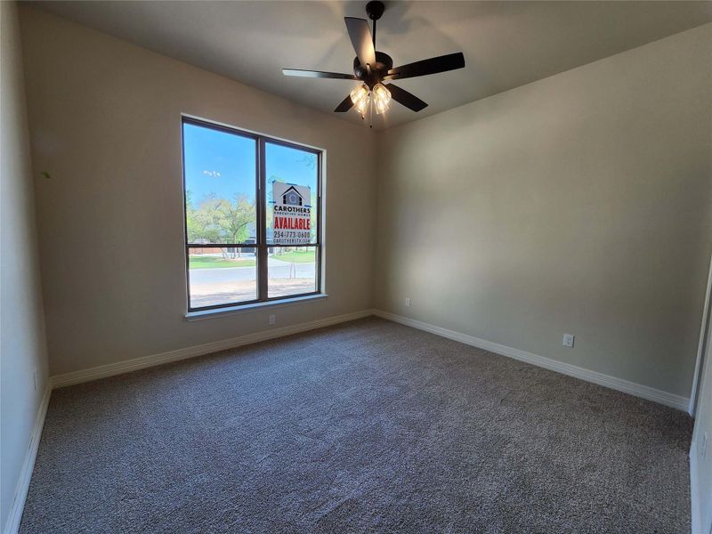 Carpeted spare room featuring a ceiling fan and baseboards