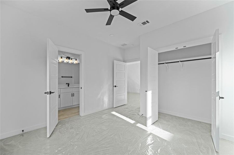 Unfurnished bedroom featuring light colored carpet, ensuite bathroom, a closet, and a ceiling fan Unfurnished bedroom featuring light colored carpet, ensuite bathroom, a closet, and a ceiling fan