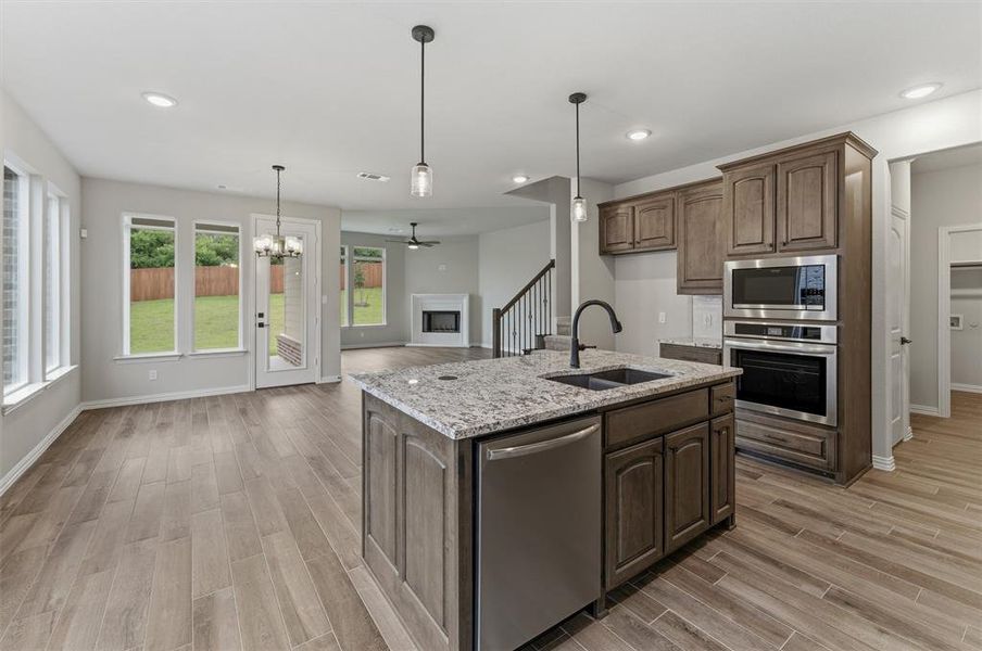 Kitchen island featuring a double-basin sink, stainless steel dishwasher, and pendant lighting