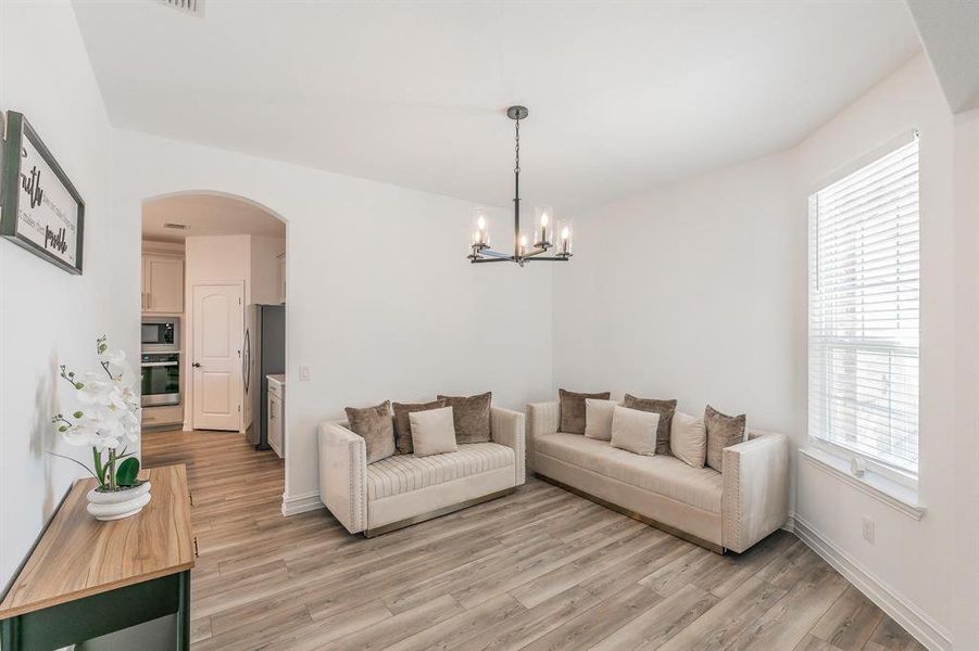 Living room featuring light wood-type flooring and a notable chandelier