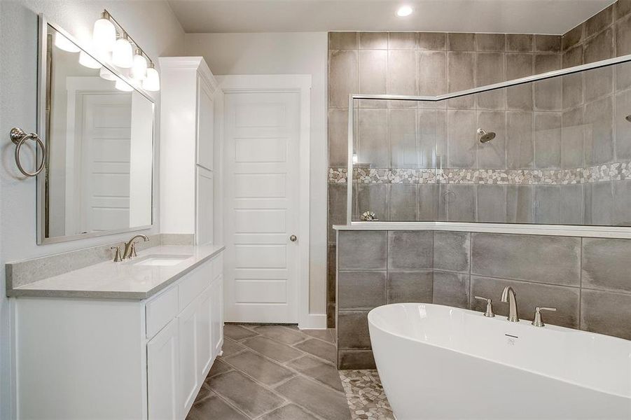 Bathroom featuring tile walls, tile floors, large vanity, and a washtub