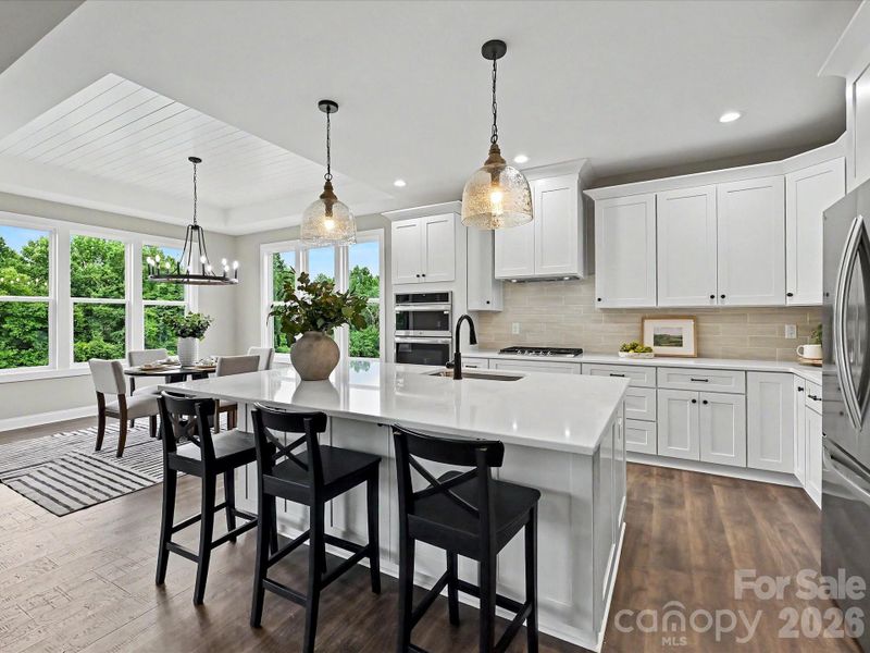 Designer kitchen features a massive quartz island, custom cabinetry, stainless steel appliances, and an open layout perfect for everyday living and entertaining.