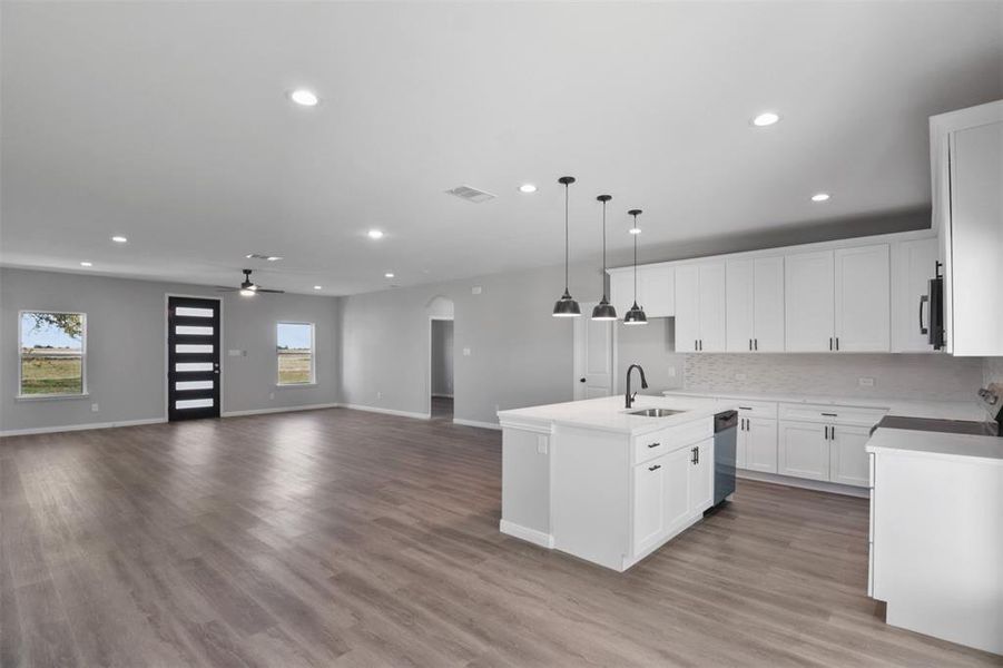 Kitchen featuring light hardwood / wood-style floors, sink, white cabinetry, and an island with sink