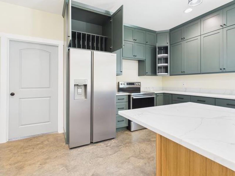 Kitchen with appliances with stainless steel finishes, light stone counters, concrete flooring, and open shelves