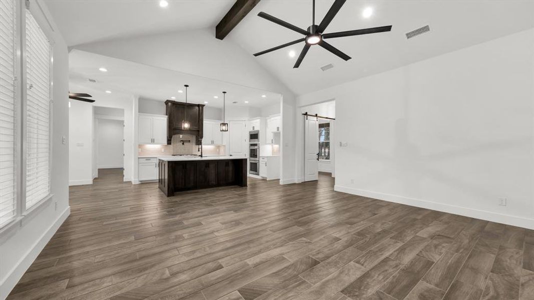 Kitchen with ceiling fan, beam ceiling, decorative light fixtures, and an island with sink