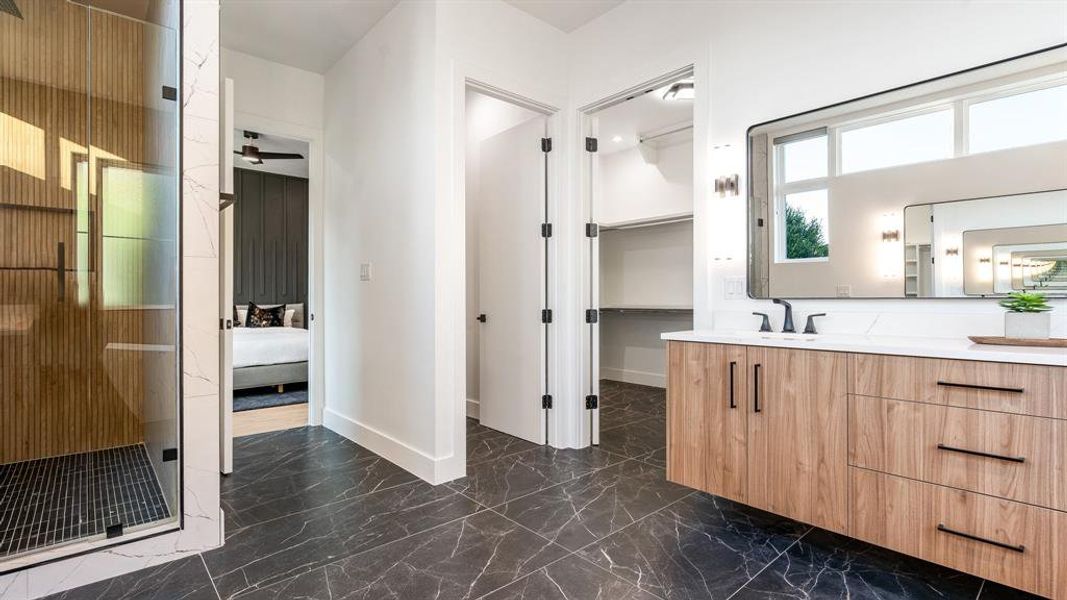 Bathroom with vanity, ceiling fan, tile floors, and a shower with door