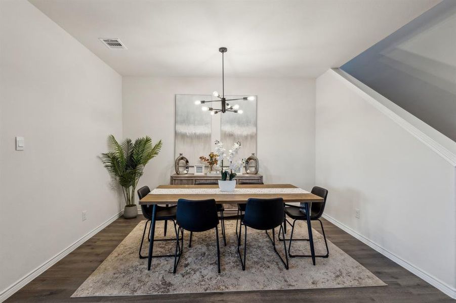 Dining room with dark hardwood / wood-style flooring and a notable chandelier