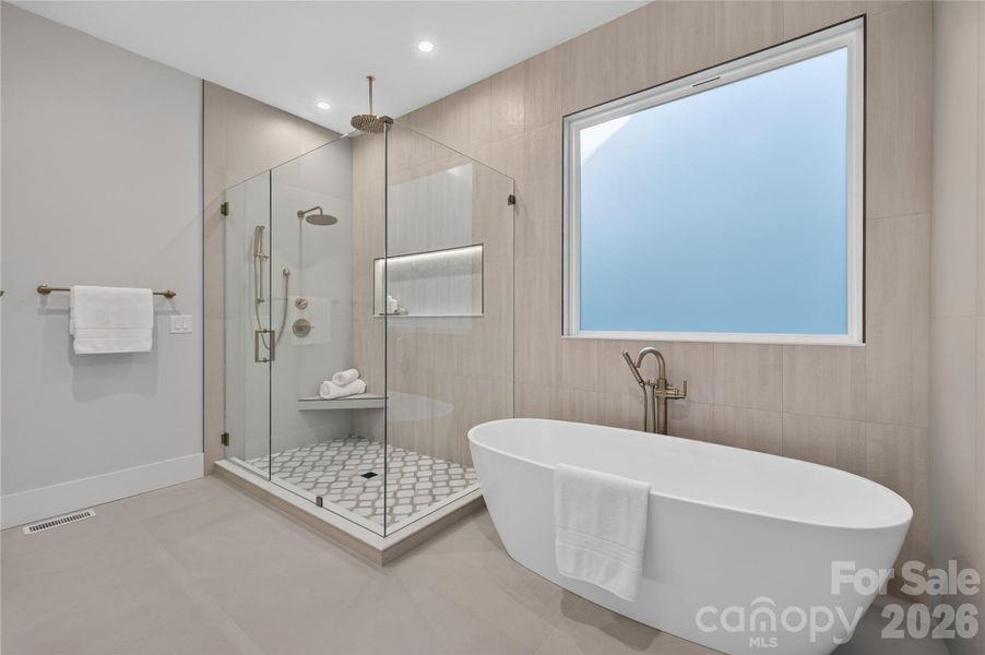 Spa inspired bathroom with soaking tub, porcelain tile, illuminated shower niche, marble shower flooring, Triple Champagne bronze shower heads.