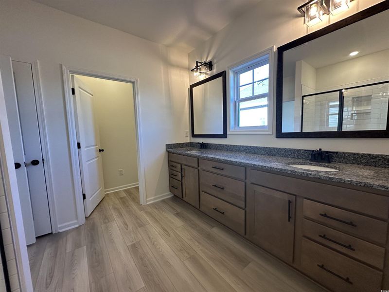 Bathroom featuring double vanity, a shower stall, and light wood-style flooring