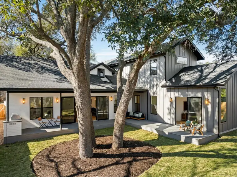 Back of house with board and batten siding, roof with shingles, a yard, and a deck