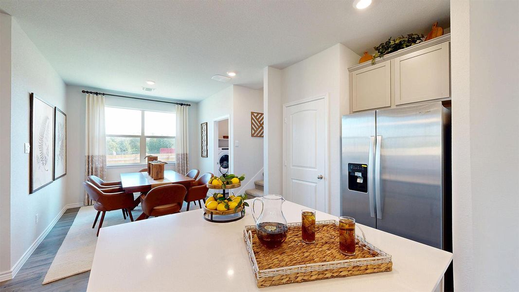Kitchen featuring stainless steel refrigerator with ice dispenser, a center island, wood finished floors, recessed lighting, and light stone countertops Kitchen featuring stainless steel refrigerator with ice dispenser, a center island, wood finished floors, recessed lighting, and light stone countertops