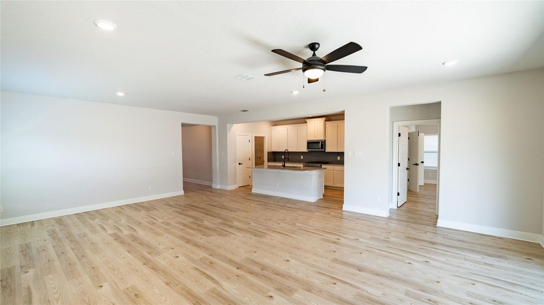 Unfurnished living room with light wood-type flooring, recessed lighting, and a ceiling fan Unfurnished living room with light wood-type flooring, recessed lighting, and a ceiling fan
