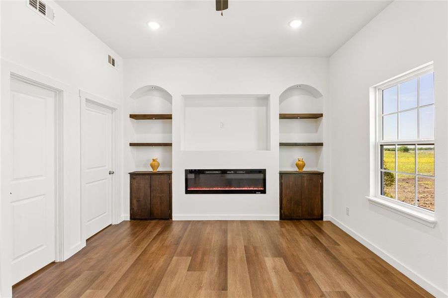 Integrated media center featuring an electric fireplace, built-in shelving, and dark wood-finish cabinetry