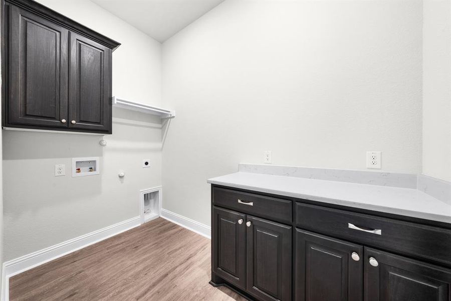 Laundry room with washer and dryer hook-ups, abundance of cabinets with countertop space for folding clothes, and luxury vinyl flooring. Laundry room with washer and dryer hook-ups, abundance of cabinets with countertop space for folding clothes, and luxury vinyl flooring.
