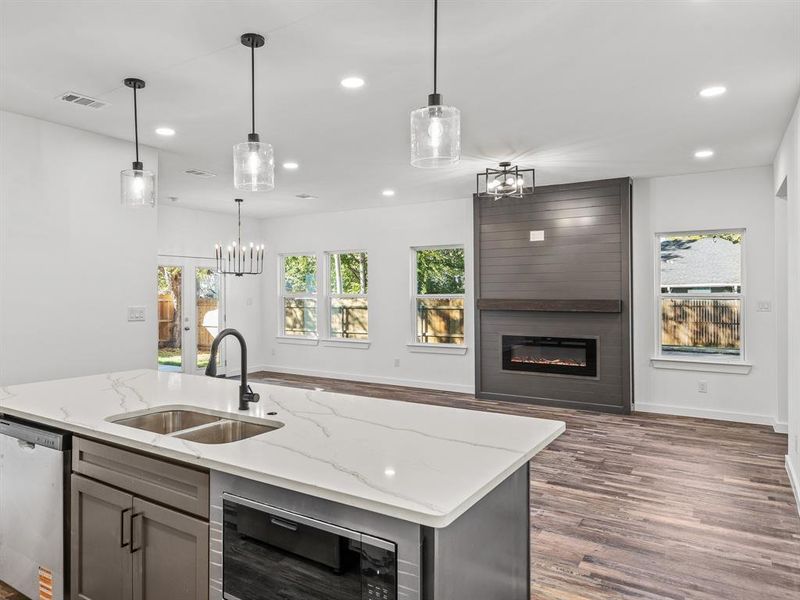 Kitchen with a fireplace, healthy amount of natural light, open floor plan, stainless steel dishwasher, and recessed lighting