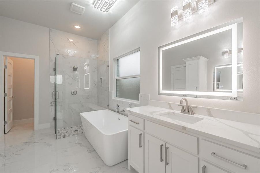 Full bath featuring a marble finish shower, vanity, light marble finish floors, a freestanding tub, and recessed lighting