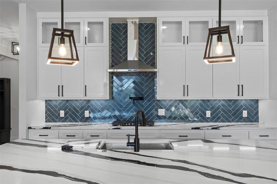 Kitchen featuring tasteful backsplash, white cabinets, and light stone countertops Kitchen featuring tasteful backsplash, white cabinets, and light stone countertops