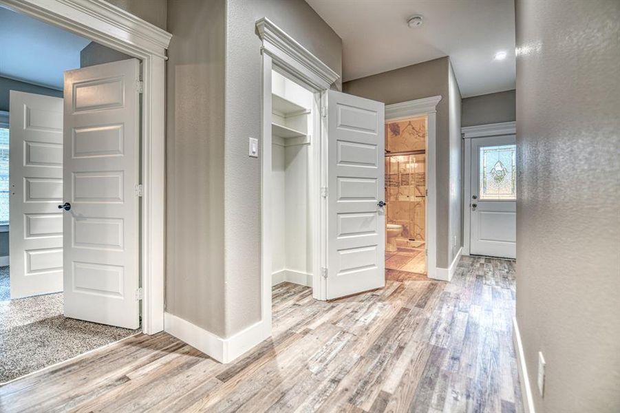 Corridor with light wood-type flooring and a textured wall