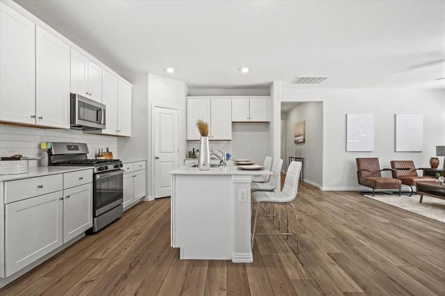 Kitchen featuring stainless steel appliances, decorative backsplash, a breakfast bar area, a center island with sink, and recessed lighting Kitchen featuring stainless steel appliances, decorative backsplash, a breakfast bar area, a center island with sink, and recessed lighting