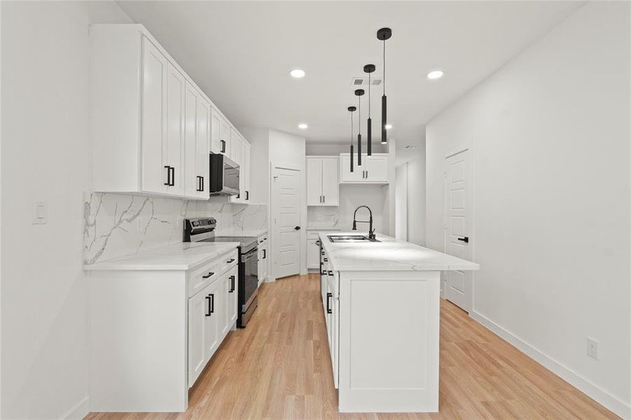 Kitchen featuring sink, white cabinetry, decorative light fixtures, a center island with sink, and appliances with stainless steel finishes