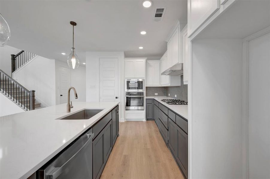 The kitchen features a spacious island with an integrated sink and faucet, complemented by white countertops and dark cabinetry