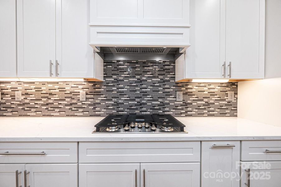 White Quartz Countertops with Grey Vein, Tile Backsplash, Gas Cooktop, Under Counter Lighting White Quartz Countertops with Grey Vein, Tile Backsplash, Gas Cooktop, Under Counter Lighting