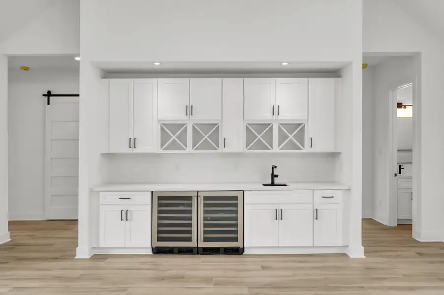 Custom wet bar with extensive cabinetry, quartz countertops, built-in sink, and dual wine refrigerators—perfect for entertaining guests.