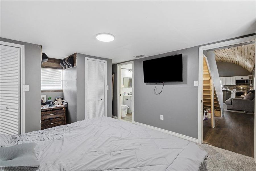 Bedroom featuring two closets, ensuite bath, and carpet floors